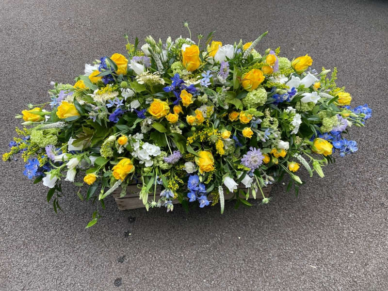 Blue and yellow funeral spray